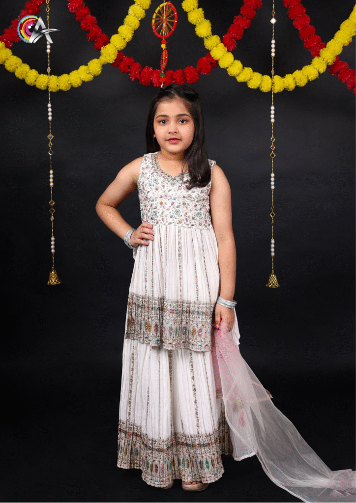 "Fashionable child model wearing a white Indian suit with delicate design and soft curls."