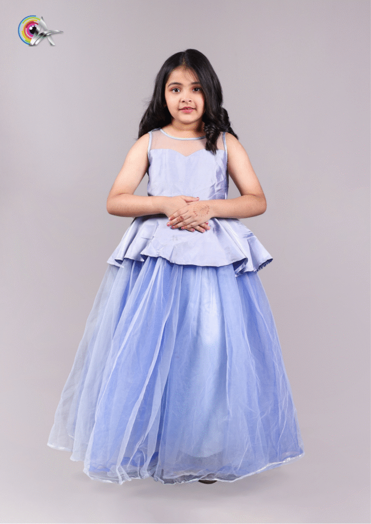 Little girl in a pastel blue party gown posing gracefully against a gray studio background.
