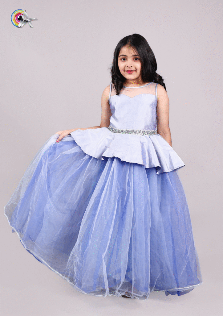 Adorable child model dressed in a shiny light blue princess gown posing for a photoshoot.