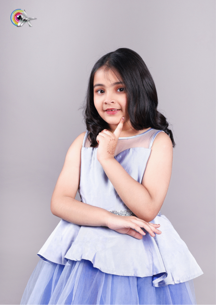Elegant little girl wearing a sky blue designer gown for kids' fashion photoshoot.